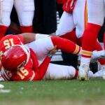 O quarterback do Kansas City Chiefs, Patrick Mahomes, segura o joelho após se machucar durante o segundo tempo de um jogo de futebol.