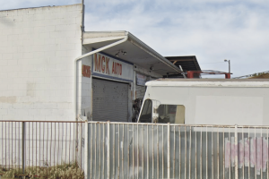 Polícia de San Diego invade sites de jogos de azar A polícia de San Diego apreende 62 caça-níqueis, drogas e dinheiro em apreensões de jogos ilegais. Exterior de uma pequena oficina de automóveis com portão de segurança de metal e uma placa dizendo “MGK Auto”, com um caminhão branco estacionado na frente, ilustrando o local conectado a uma apreensão de jogos ilegais da polícia de San Diego, onde máquinas caça-níqueis, drogas e dinheiro foram apreendidos.