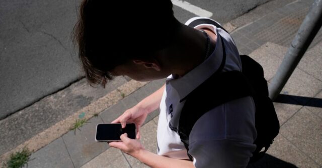 Um adolescente usa seu telefone nas redes sociais em Sydney, 8 de novembro de 2024.