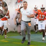 O técnico do Miami, Mario Cristobal, conduz os jogadores para o campo antes do jogo contra o Syracuse.