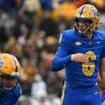 Jogador de futebol americano do Pittsburgh Panthers vestindo uniforme azul e amarelo com o número 6.