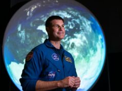 Próxima parada, a lua! Artemis II começa a parecer ‘muito real’ para o astronauta Jeremy Hansen Um homem e uma mulher em um palco com a apresentação de uma viagem à lua atrás deles.