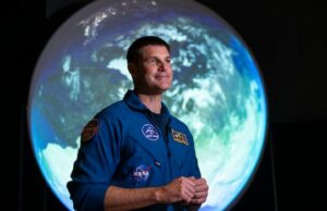 Próxima parada, a lua! Artemis II começa a parecer ‘muito real’ para o astronauta Jeremy Hansen Um homem e uma mulher em um palco com a apresentação de uma viagem à lua atrás deles.