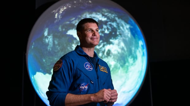 Próxima parada, a lua! Artemis II começa a parecer ‘muito Um homem e uma mulher em um palco com a apresentação de uma viagem à lua atrás deles.