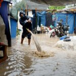 Máquinas pesadas operam enquanto palestinos se reúnem em uma pilha de escombros em busca de vítimas em uma casa destruída que desabou durante fortes chuvas, em Beit Lahia, no norte da Faixa de Gaza, 12 de dezembro de 2025. (Mahmoud Issa/Reuters)