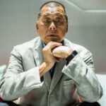 Jimmy Lai, de terno cinza e calça preta, posa para uma fotografia durante entrevista à agência de notícias AFP em Hong Kong