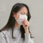 Mãe hispânica e filho adolescente conversando seriamente em seu quarto, ambos sentados na cama.