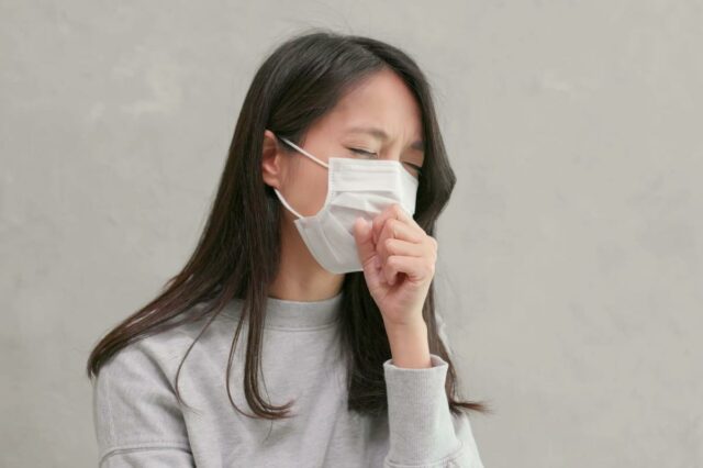 Mãe hispânica e filho adolescente conversando seriamente em seu quarto, ambos sentados na cama.