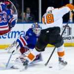 O goleiro do New York Rangers, Igor Shesterkin, defende a rede contra o pivô do Philadelphia Flyers, Rodrigo Abols.