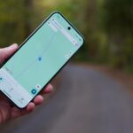 Um carro navegando pelo ícone MAPS.ME com uma linha de rota azul, contra um fundo geométrico amarelo claro.