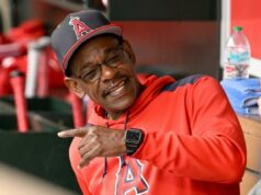 Ron Washington assume o cargo de técnico de campo do Giants depois de perder a maior parte de 2025 devido a problemas médicos Ron Washington com um moletom vermelho e boné do Los Angeles Angels, sorrindo e apontando para o banco de reservas.