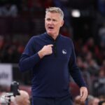 Jonathan Kuminga, do Golden State Warriors, à direita, dirige contra Jaylon Tyson, do Cleveland Cavaliers, à esquerda, durante a primeira metade de um jogo de basquete da NBA em Cleveland, sábado, 6 de dezembro de 2025. (AP Photo/Phil Long)