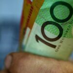 Alguém segurando um punhado de notas de US$ 50 e US$ 100.