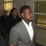 Terry Rozier pede ao juiz que rejeite as acusações no caso federal de apostas da NBA. O guarda do Miami Heat, Terry Rozier, vestindo um terno cinza, caminha ao lado de outras pessoas do lado de fora de um tribunal federal à noite após sua acusação.