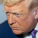 O presidente da Câmara dos EUA, Mike Johnson, segura seu telefone celular perto do microfone enquanto o presidente Donald Trump fala depois de ligar para ele antes de apresentar o candidato republicano ao Congresso dos EUA para o sétimo distrito, Matt Van Epps, durante um comício na segunda-feira, 1º de dezembro de 2025, em Franklin, Tennessee.