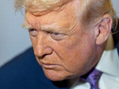 Trump corre para resgatar o Partido Republicano em eleições especiais surpreendentemente apertadas O presidente da Câmara dos EUA, Mike Johnson, segura seu telefone celular perto do microfone enquanto o presidente Donald Trump fala depois de ligar para ele antes de apresentar o candidato republicano ao Congresso dos EUA para o sétimo distrito, Matt Van Epps, durante um comício na segunda-feira, 1º de dezembro de 2025, em Franklin, Tennessee.