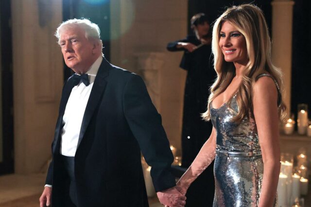 Donald e Melania Trump caminham juntos de mãos dadas.