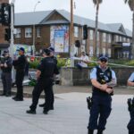 A polícia e transeuntes carregam uma vítima ferida do tiroteio em massa de Bondi.