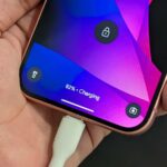 Etiqueta Qi2 com carregador na parte traseira de um telefone em um fundo azul claro e médio