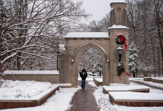 Uma pessoa atravessa Sample Gates no campus da Universidade de Indiana na terça-feira, 2 de dezembro de 2025,