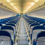 A stock image showing an aisle view of an empty commercial aircraft.