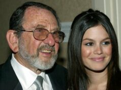 Bruce Bilson, diretor vencedor do Emmy por ‘Get Smart’ e ‘Hogan’s Heroes’, morre aos 97 Uma mulher loira está rindo e segurando um cachorrinho vestido com uma roupa roxa e rosa. Ela está vestida com uma jaqueta rosa brilhante, óculos escuros vermelhos e um telefone rosa preso à orelha. O fundo mostra um ambiente externo desfocado com pessoas e vegetação.