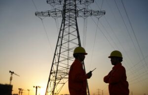 A administração Trump quer que as empresas de tecnologia comprem US$ 15 bilhões em usinas de energia que não podem usar Two workers inspect high-tension power lines.