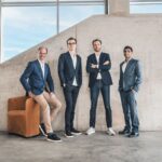 Four men standing in front of a concrete wall.