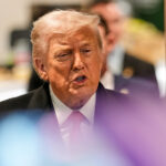 Uma pessoa segura uma bandeira do estado de Minnesota enquanto oficiais federais de imigração lançam gás lacrimogêneo no sábado, 24 de janeiro de 2026, em Minneapolis. (Foto AP/Abbie Parr)