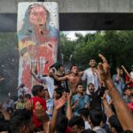 ARQUIVO- Manifestantes gritam slogans enquanto comemoram a renúncia da primeira-ministra Sheikh Hasina, em Dhaka, Bangladesh, segunda-feira, 5 de agosto de 2024. (AP Photo/Rajib Dhar, Arquivo)