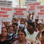 Uma mulher cristã indiana recebe a sagrada comunhão enquanto outras pessoas esperam na fila durante o Natal na igreja St. Mary's Garrison, em Jammu, Índia, quinta-feira, 25 de dezembro de 2025. (AP Photo/Channi Anand)
