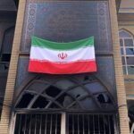 Os destroços de um ônibus queimado são vistos em uma rua.