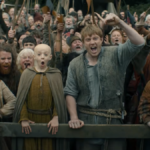 Um homem e um menino estão diante de uma grande multidão, aplaudindo.