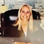 Rachel Green sorrindo enquanto está sentada em uma mesa.