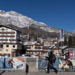Pessoas passam por cartazes dos Jogos Olímpicos de Inverno de Milão Cortina 2026 em Cortina d'Ampezzo, Itália.