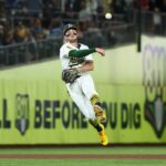 O shortstop de atletismo Jacob Wilson lança uma bola de beisebol para a primeira base.