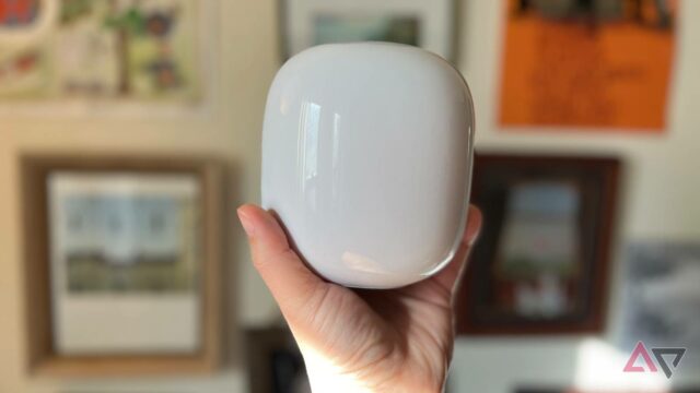 Segurando o Google Nest Wifi Pro com fotos e arte em segundo plano