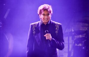 Barry Manilow compartilha boas notícias com os fãs após revelar o diagnóstico de câncer Barry Manilow se apresentando no palco com um microfone.