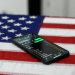 Bilhões de receitas fiscais seriam geradas se todos os estados legalizassem as apostas. Smartphone exibindo a interface de um aplicativo de apostas esportivas apoiada em uma bandeira americana, simbolizando as apostas esportivas online e sua regulamentação nos Estados Unidos.