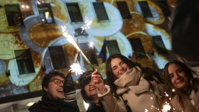 Os passageiros passam por um anúncio promovendo a entrada da Bulgária na zona do euro no metrô de Sófia em 31 de dezembro de 2025, antes da adoção do euro pelo país em 1º de janeiro de 2026. (Foto de Nikolay DOYCHINOV / AFP)