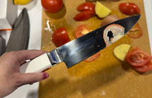 CES 2026: Esta faca tem um truque secreto de festa. Ele vibra quando você corta com ele. uma mulher cortando um tomate com a faca de chef ultrassônica Seattle Ultrasonics C-200