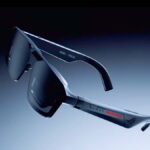 Esquerda: óculos para jogos ROG Xreal R1 AR. À direita: óculos para jogos ROG Xreal R1 AR acoplados em uma mesa ao lado de um teclado, fones de ouvido e um controlador.