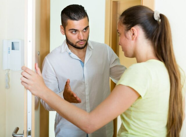 Um casal conversando perto de uma porta.