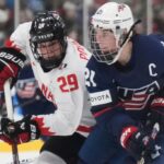 ARQUIVO- A atacante dos Estados Unidos Hilary Knight (21) e a atacante do Canadá Marie-Philip Poulin (29) batalham durante o segundo período do jogo pela medalha de ouro no campeonato mundial feminino de hóquei em Brampton, Ontário, domingo, 16 de abril de 2023. (Nathan Denette/The Canadian Press via AP, Arquivo)