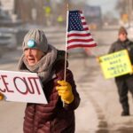 Mark Dion fala em um pódio, cercado por autoridades municipais