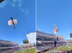 Cena chocante quando um pára-quedista é preso na rede do gol em um jogo de boliche Um pára-quedas com um pára-quedas branco e azul preso em uma rede de cesta acima de um estádio.