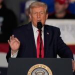 Donald Trump fala em um pódio com um microfone.