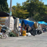 Tendas alinham-se na rua de um acampamento de moradores de rua.
