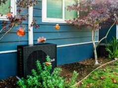 Como a Quilt resolveu o maior desafio da bomba de calor A dark grey heat pump sits outside a blue home.