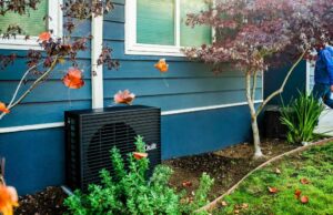 Como a Quilt resolveu o maior desafio da bomba de calor A dark grey heat pump sits outside a blue home.